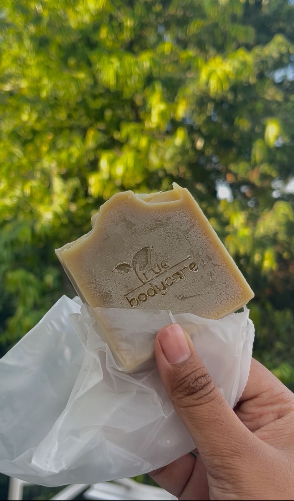 Perbandingan makro microbeads plastik biru bulat mengkilap versus bubuk kopi organik coklat kasar tidak beraturan dari Dewijaya Care di atas daun pisang